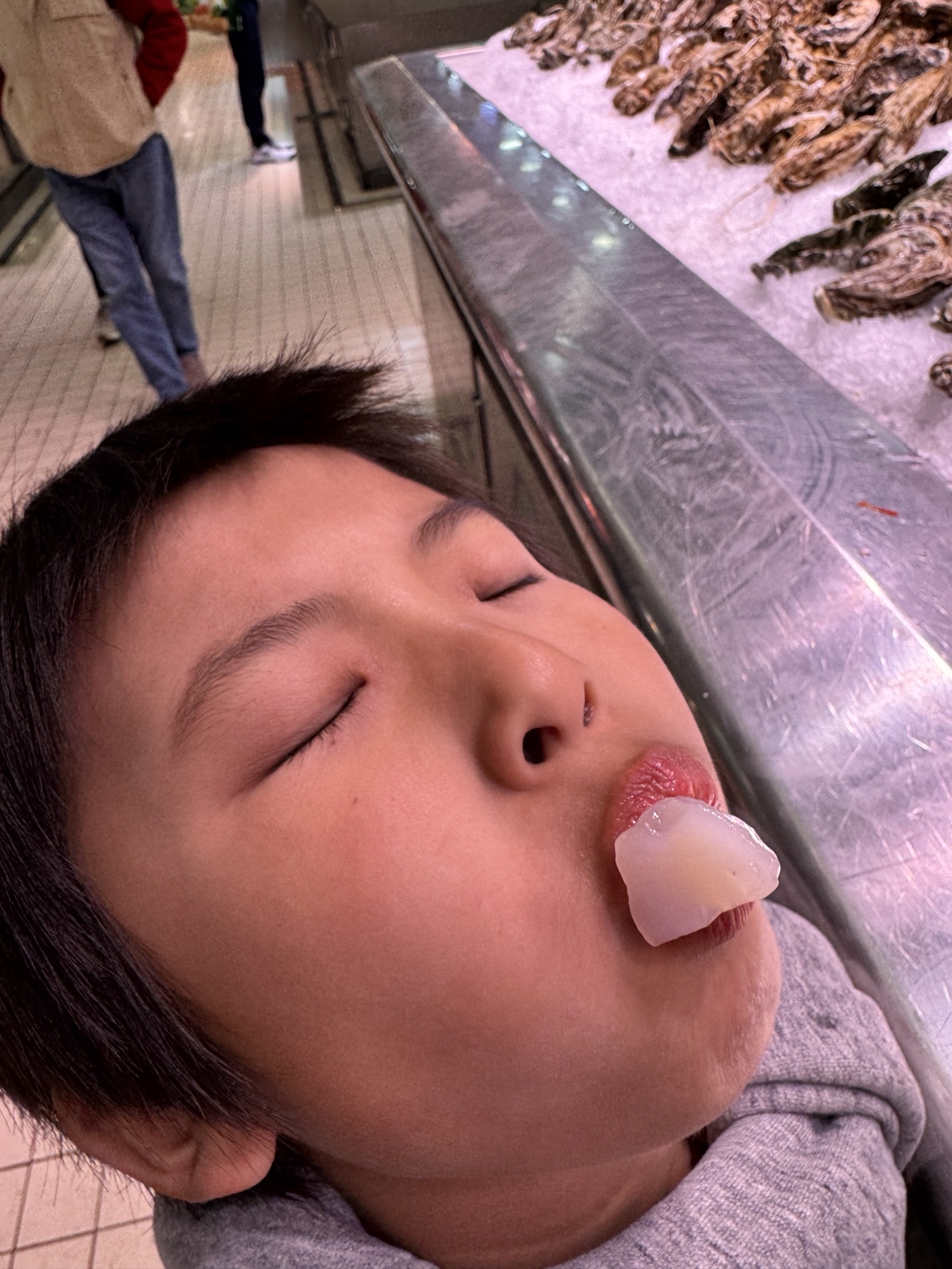 孩子在中央市場海鮮攤前搞怪試吃